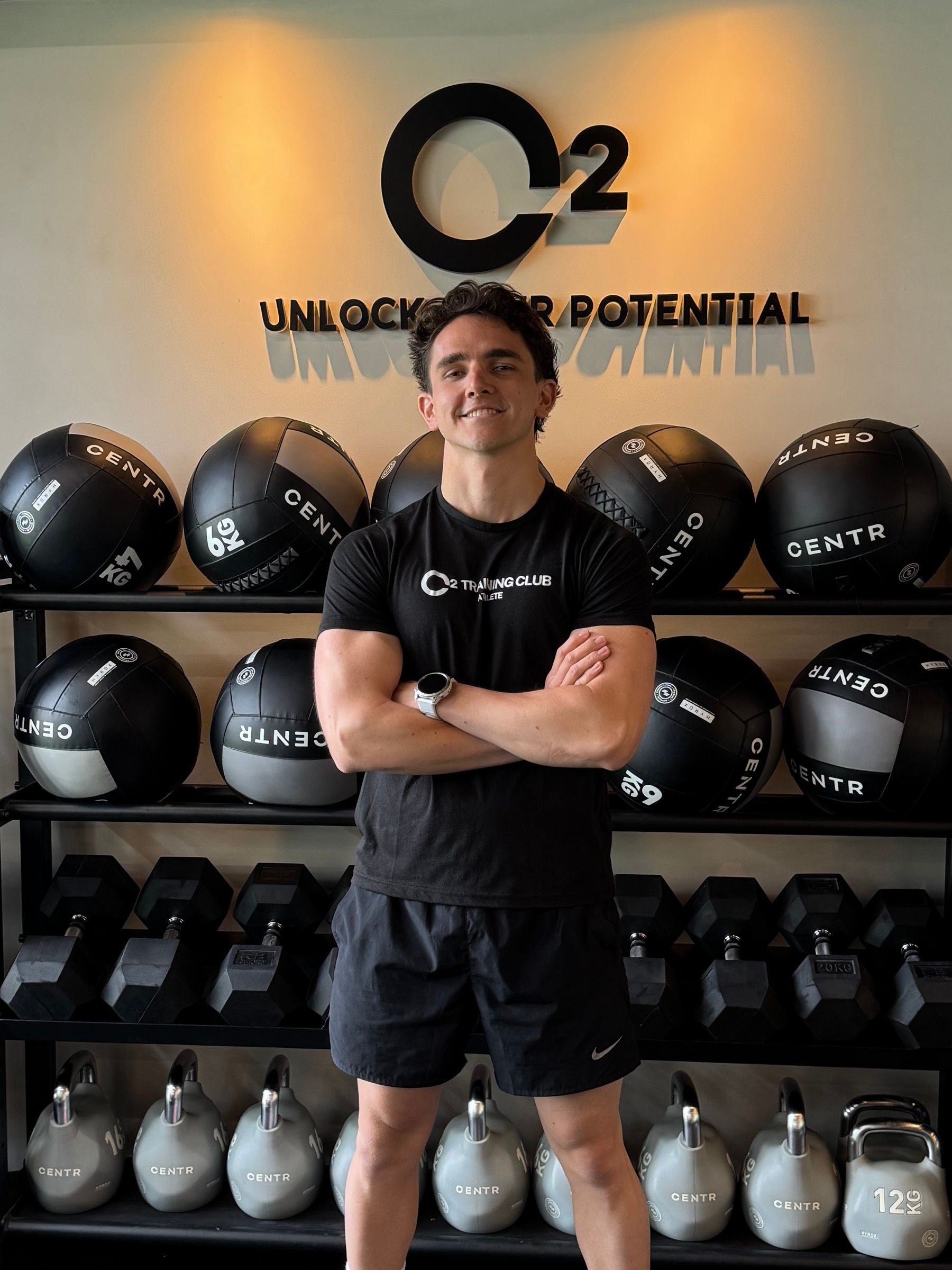 Mateho, coach sportif, bras croisés dans sa salle d’entraînement.